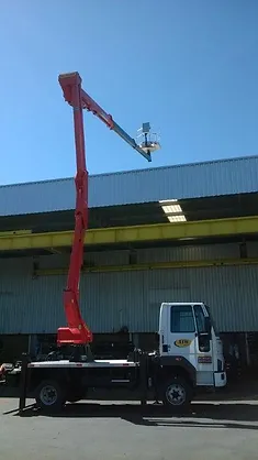 Caminhão Madal Palfinger P240A da ATW Brasil com a plataforma aérea estendida em um ambiente de trabalho.